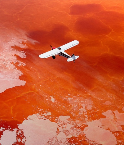 Image of Gallet pilot driving small plane above red lake image