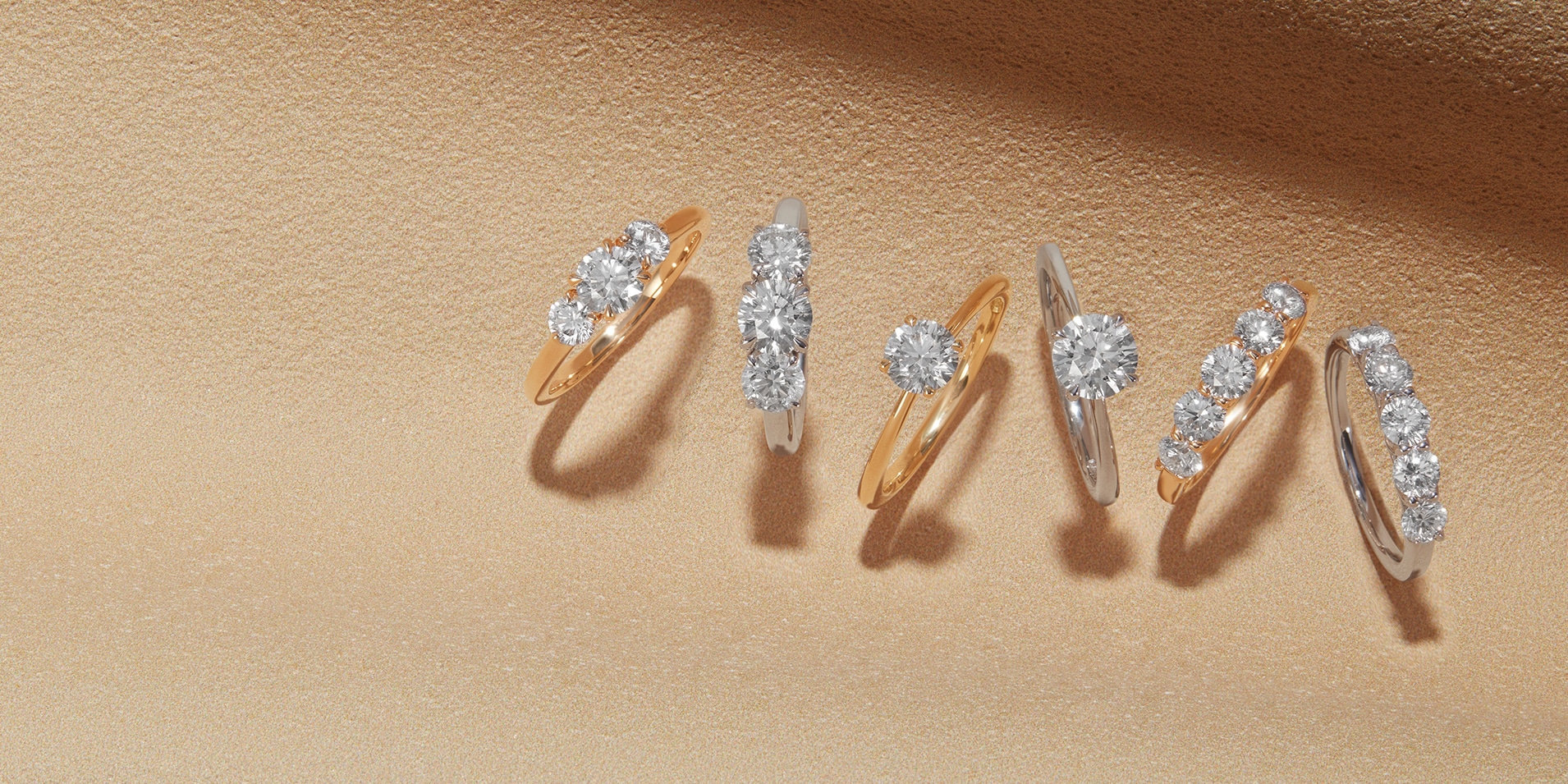Goldsmiths Signature Diamond rings on sandy background