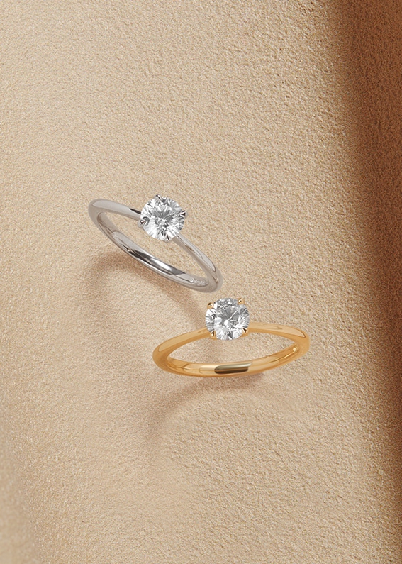 Goldsmiths Signature Diamond Solitaire Rings on sandy background