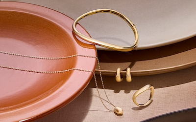 Image of yellow gold necklaces, earrings, bracelet and ring in terracotta coloured bowl. Tap to shop all jewellery image