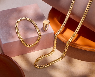 Image of yellow gold necklaces, bracelet and ring in terracotta coloured bowl. Tap to shop all mens jewellery image